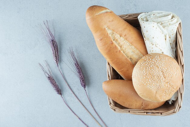 Varietà di pane in cestino e grano sulla superficie di pietra