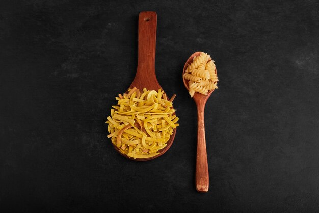 Varietà di pasta in cucchiai di legno.