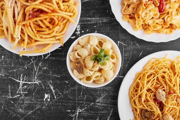 Varietà di pasta in salsa di pomodoro in un piatto bianco su sfondo nero.