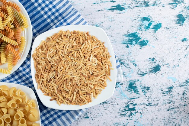 Varietà di pasta secca su piatti bianchi. Foto di alta qualità