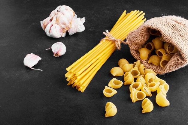 Varietà di pasta sul nero con spicchi d'aglio da parte.
