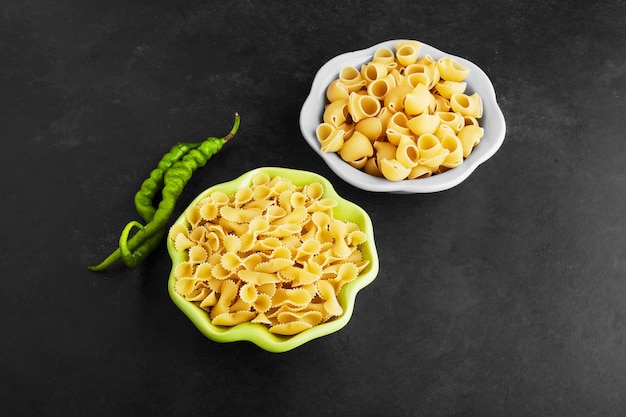 Varietà di pasta sul nero in bocce blu e verdi.