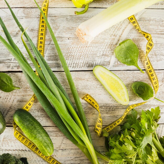 Vario cibo sano verde con nastro adesivo di misurazione sulla tavola di legno