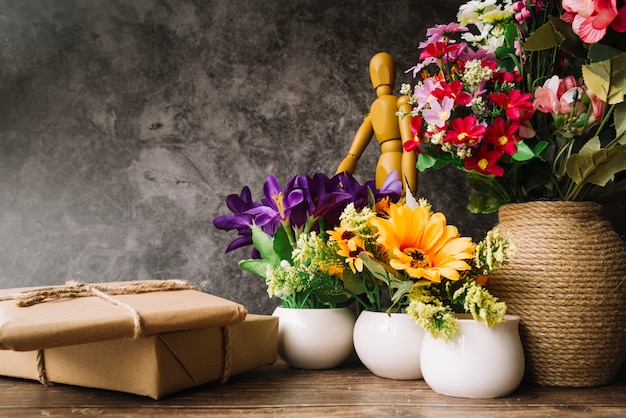 Vasi di fiori con figura fittizia di legno e scatole regalo sul tavolo di legno