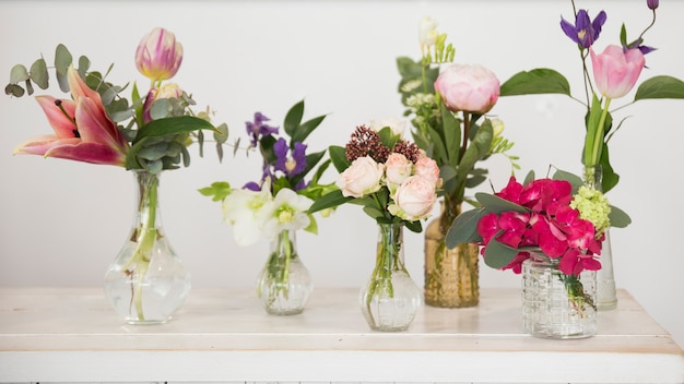 Vasi di fiori freschi sulla scrivania su sfondo bianco