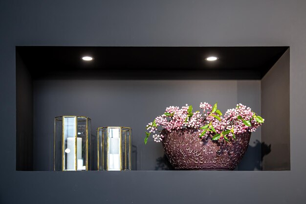Vaso del primo piano con fiori e candelieri di vetro nell'interiore domestico