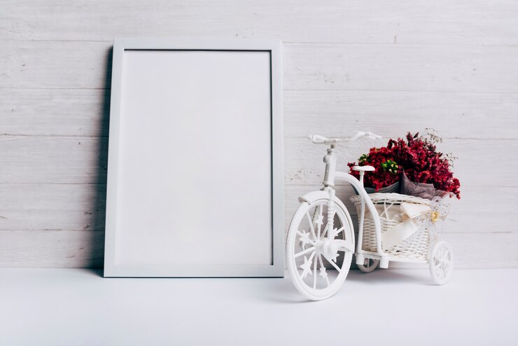 Foto gratuito vaso di fiori con la bicicletta vicino al telaio bianco bianco sulla scrivania