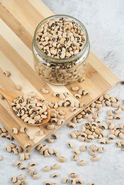 Vaso di vetro di fagioli bianchi su tavola di legno.