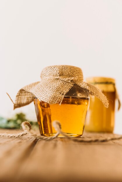 Vaso di vetro pieno di miele sul tavolo di legno