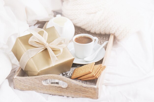 Vassoio della colazione con caffè, biscotti e un regalo d&#39;oro