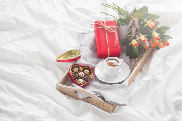 Vassoio della colazione con un dono, fiori e cioccolatini