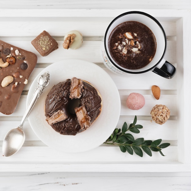 Vassoio in legno con colazione e assortimento di cioccolata su piatto disteso