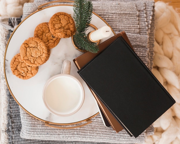 Vassoio vista dall'alto con biscotti, latte e libri