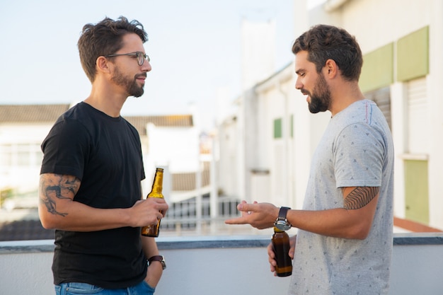 Vecchi amici maschii che bevono birra e conversazione