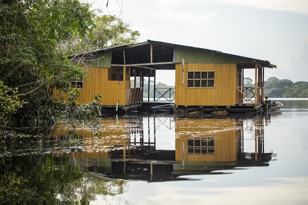 Vecchia cabina di legno gialla esposta all'aria in riva al lago circondata da una splendida vegetazione