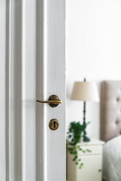 Vecchia serratura e manopola su una porta di legno bianca della stanza sotto le luci