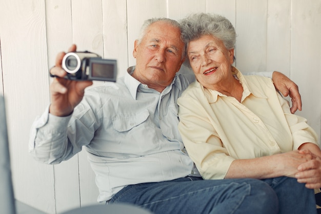 Vecchie coppie eleganti che si siedono a casa e che per mezzo di una macchina fotografica