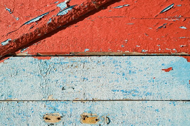 Vecchie tavole di legno con sfondo di vernice rossa e blu scrostata per il design o i social media