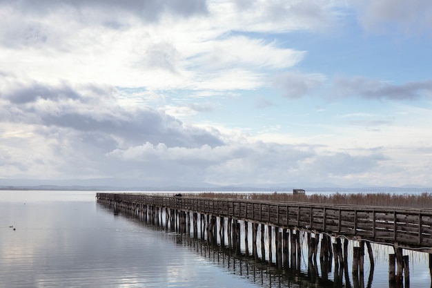 Vecchio pontile di legno che si estende nel mare sotto un cielo nuvoloso