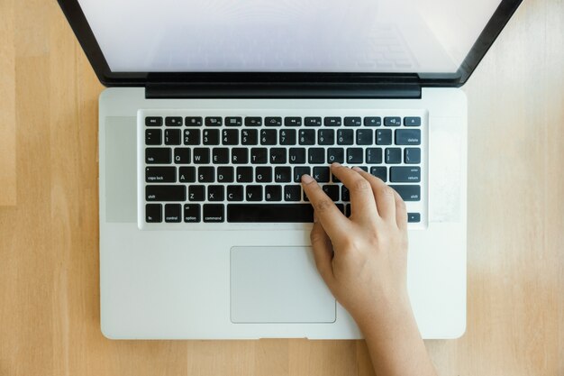 Veduta aerea della donna digitando lavorando su un computer portatile bianco su un tavolo di legno. Immagini di stile d&#39;effetto vintage.