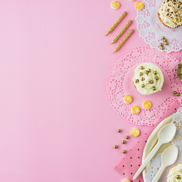 Veduta dall&#39;alto di cupcakes; caramelle e candele su sfondo rosa