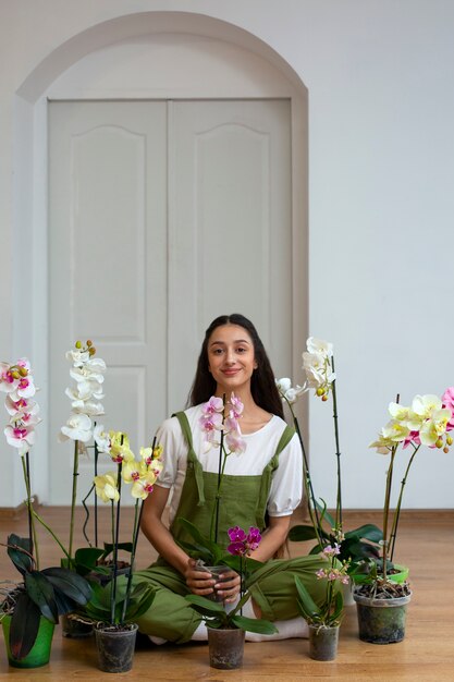 Veduta di una donna che decora la sua casa con un fiore di orchidea