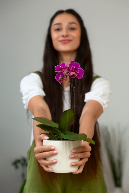 Veduta di una donna che decora la sua casa con un fiore di orchidea