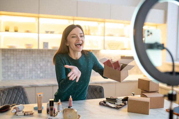 Vendita. Giovane donna in abito verde che conduce vendita di cosmetici online