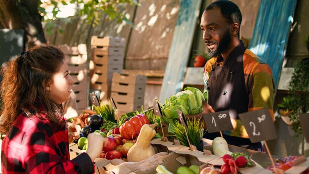 Venditore del mercato degli agricoltori che distribuisce ai clienti scatole di prodotti biologici stagionali