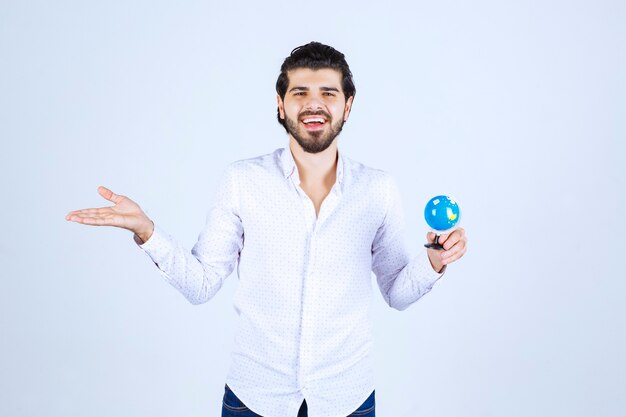 Venditore in possesso di un mini globo e promuovere il prodotto