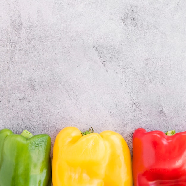 Verde; peperone giallo e rosso su sfondo grigio cemento