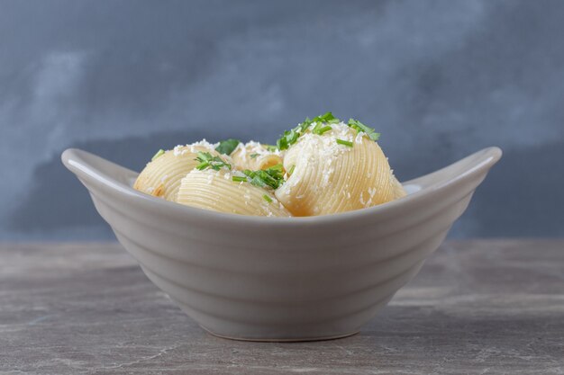 Verdi e pasta piccante in ciotola, sulla superficie di marmo.