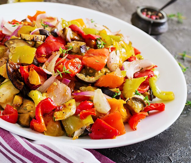 Verdure al forno sul piatto bianco. Melanzane, zucchine, pomodori, paprika e cipolle