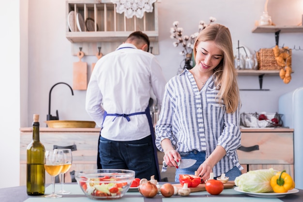 Verdure di taglio della giovane donna in cucina