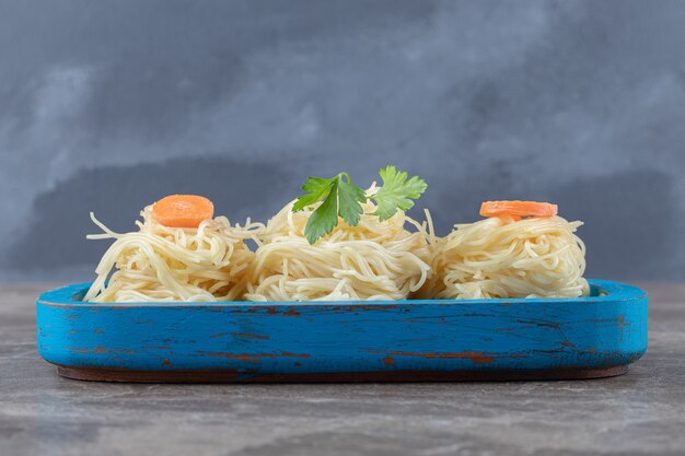 Verdure e carote grattugiate sugli spaghetti, sulla tavola di legno, sul marmo.