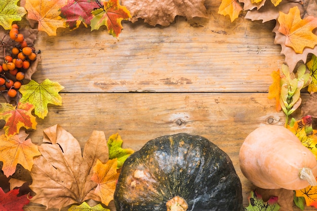 Verdure e foglie secche su tavola di legno