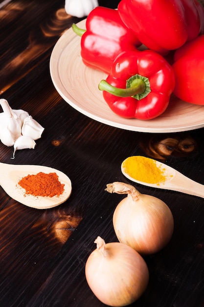 Verdure e spezie in polvere su tavola di legno bruciata