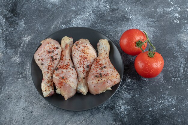 Verdure fresche con cosce di pollo su sfondo grigio.