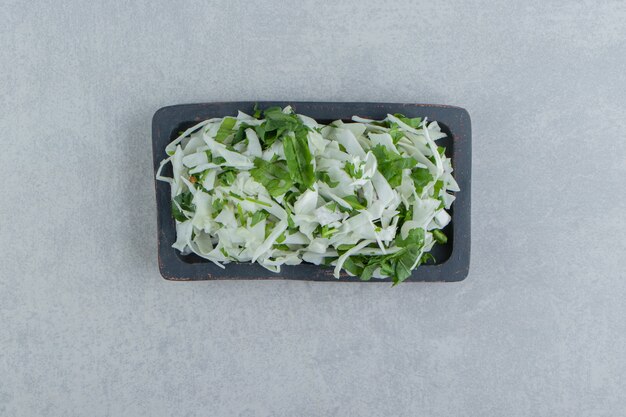 Verdure fresche e cavoli tritati in una ciotola, sullo sfondo di marmo.