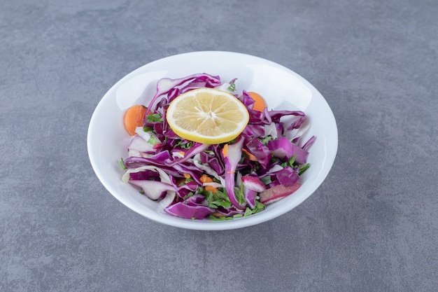 Verdure grattugiate con limone sul piatto, sulla superficie di marmo.