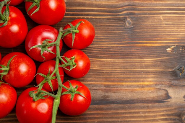 Verdure mature dei pomodori rossi di vista ravvicinata superiore sulla dieta fresca matura dell'insalata rossa dello scrittorio di legno marrone