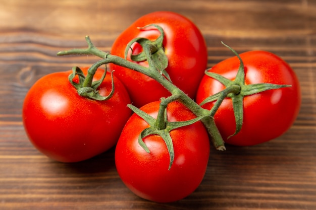 Verdure mature dei pomodori rossi di vista vicina anteriore sull'insalata fresca matura rossa di dieta dello scrittorio marrone