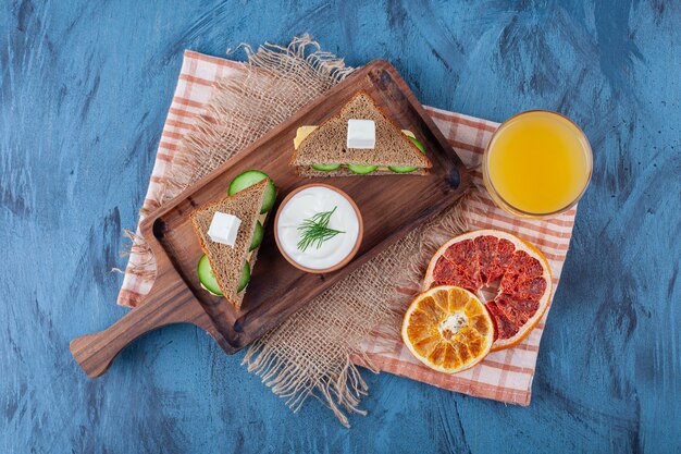 Verdure secche accanto a un bicchiere di succo, panino, su una tavola su un tovagliolo di tela, sul blu.