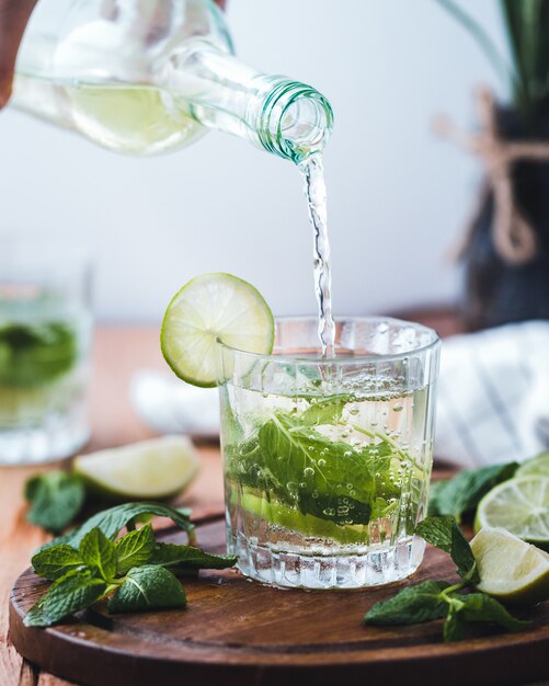 Versare acqua con lime in una tazza di vetro