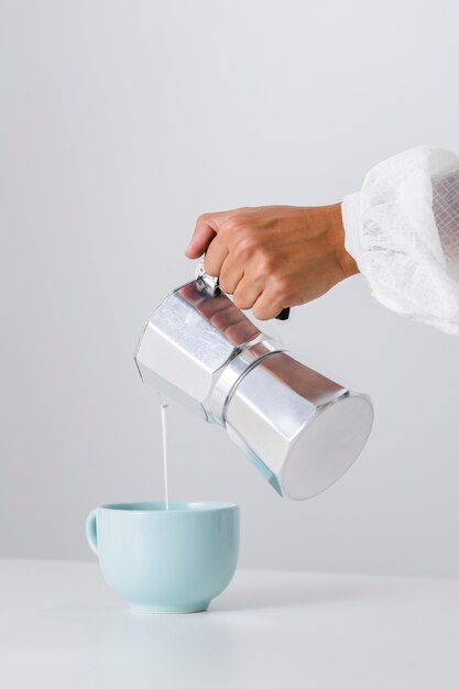 Versare il latte in una tazza di ceramica