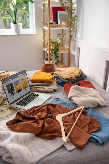 Vestiti ad alto angolo e laptop sul letto