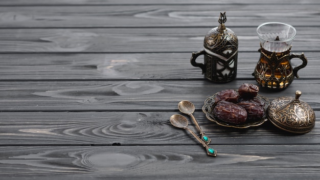 Vetri di tè arabi tradizionali turchi e datteri secchi con cucchiai sulla tavola di legno