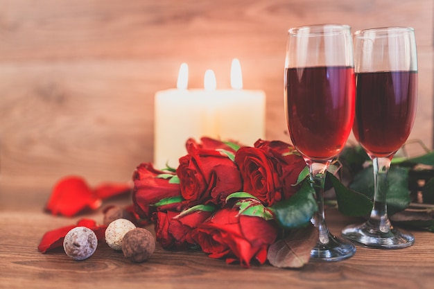 Vetri di vino con candele accese e un mazzo di rose