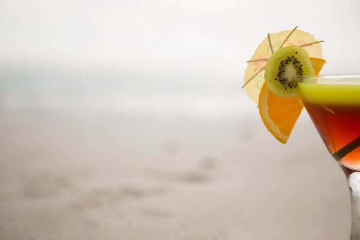 Vetro di bere cocktail guarnito con kiwi, calce e cocktail ombrello