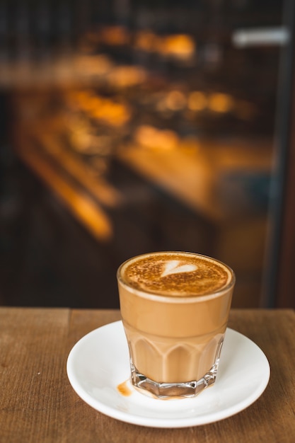 Vetro di latte saporito con arte di amore sulla tavola di legno in caffetteria